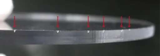 Närbild på plexiglas med markerade skärmärken.